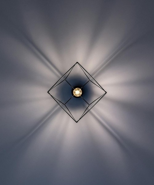 A minimalist geometric ceiling light with striking light and shadow patterns.
